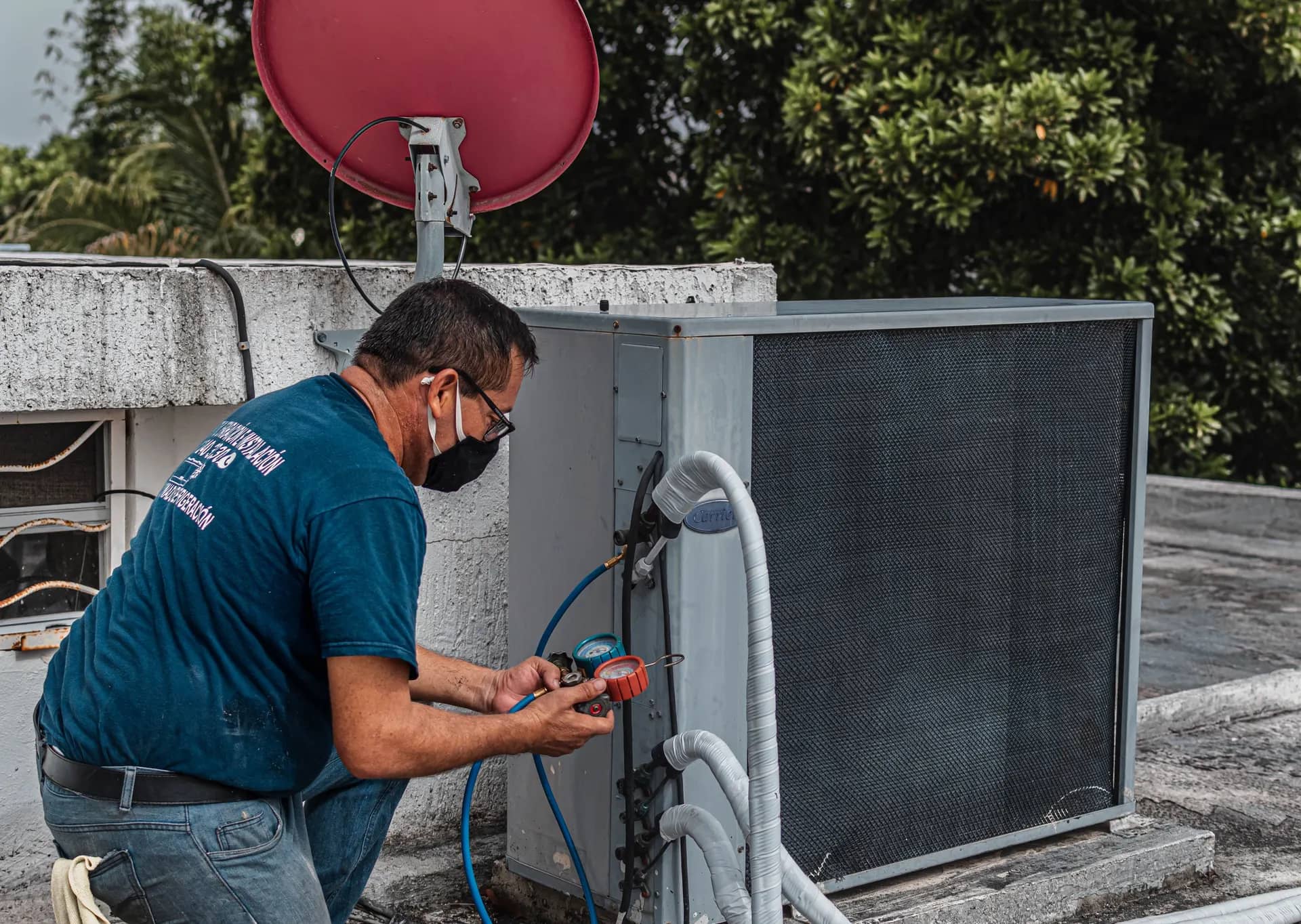 Technician checking refrigerant pressures at an outdoor air-conditioning unit