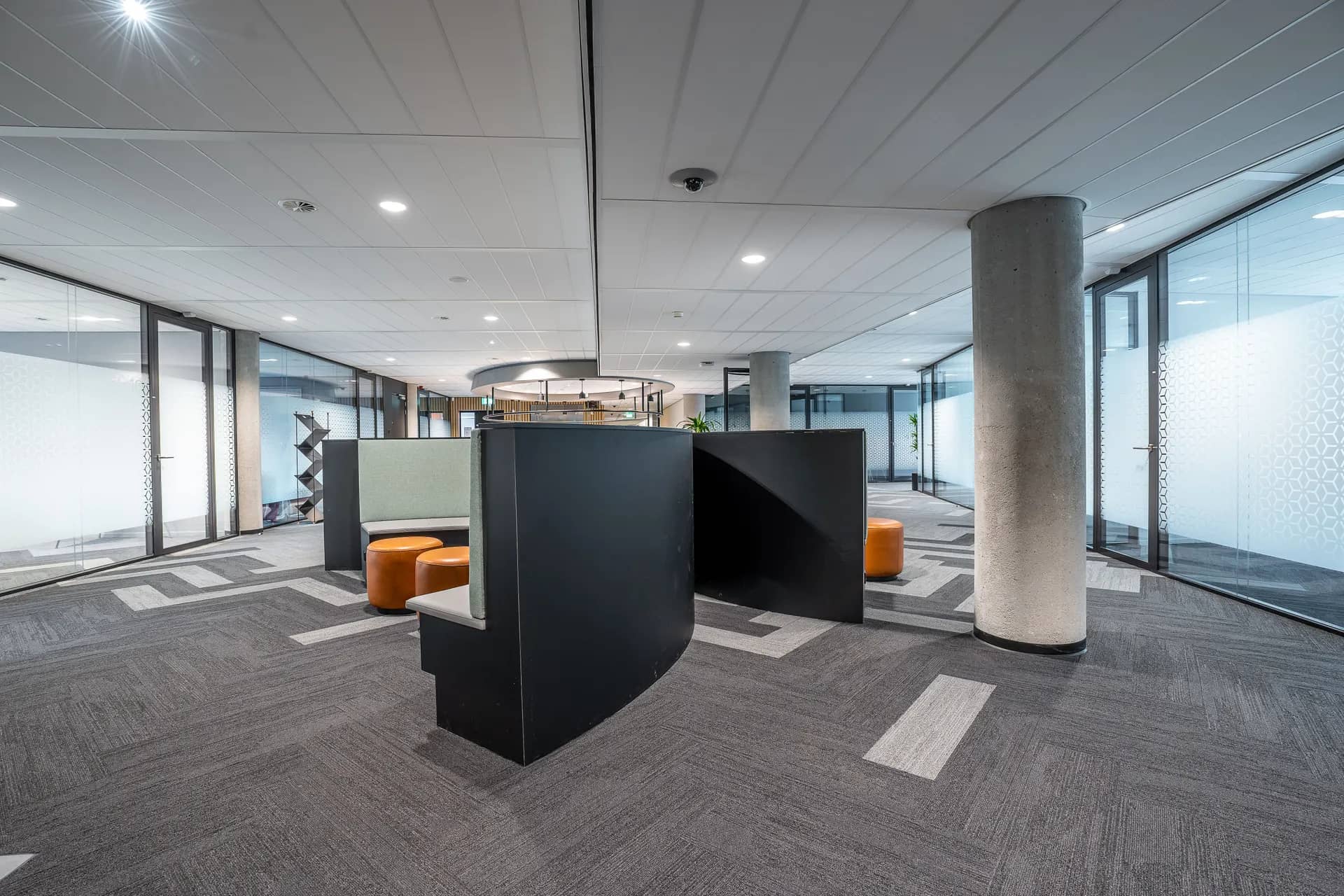 Open office floor with workstations, glass partitions and a suspended ceiling